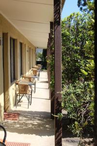a row of tables and chairs on the side of a building at Colonial Motor Inn Pambula in Pambula