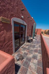 ein rotes Gebäude mit einem gefliesten Gang in der Wüste in der Unterkunft Island Cottage Guesthouse in Lüderitz