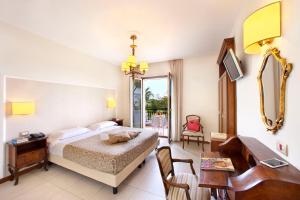 a bedroom with a bed and a desk and a mirror at Hotel Alpha in Sant'Agnello