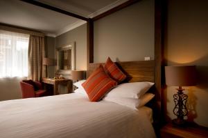 um quarto com uma cama grande com almofadas laranja e branca em Crouchers Hotel em Chichester