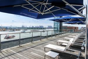 a patio area with chairs, tables and umbrellas at Clipper Boardinghouse - Hamburg-Holzhafen in Hamburg