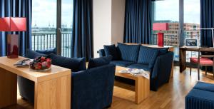 a living room with blue furniture and a large window at Clipper Boardinghouse - Hamburg-Holzhafen in Hamburg