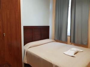1 dormitorio con 1 cama con sombrero en Albergue A Ponte Ribadeo en Ribadeo