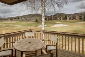 uma mesa de madeira e cadeiras num deque com um campo de golfe em Ridge 91 em Elkhorn Village