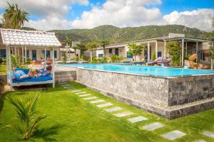 a swimming pool in a yard with people laying on chairs near a house at Sorrento Beach Club & Kite Village in Phan Rang +11 photos