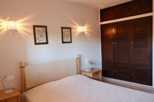 a bedroom with a bed and two lights on the wall at Peaceful & Spacious Apt with Parking & Queen Bed in Carvoeiro