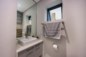 uma casa de banho com um lavatório e um espelho em Seacrest Luxury Beachfront Apartment - Blouberg Beach em Bloubergstrand