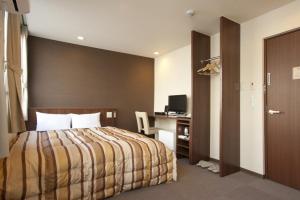 a hotel room with a bed and a desk at Hotel Kudou Oita in Oita