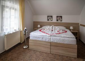 Un dormitorio con una gran cama blanca con flores rojas. en Pension Coloseum, en Pruhonice