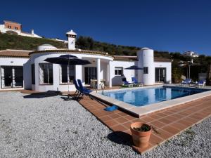 a villa with a swimming pool in front of a house at Belvilla by OYO Vista Maravilla in Arenas