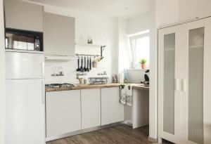 a kitchen with white cabinets and a white refrigerator at Sunny City Center Apartment in Warsaw