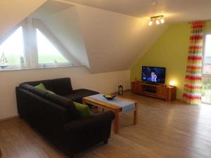 a living room with a couch and a tv at Ferienwohnung Regenbogenhaus in Hasselberg