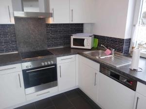 a white kitchen with a sink and a microwave at Ferienwohnung Regenbogenhaus in Hasselberg