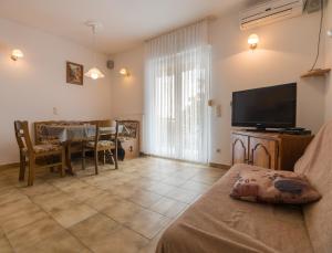 ein Wohnzimmer mit einer Couch, einem Fernseher und einem Tisch in der Unterkunft 689 Banjol in Rab