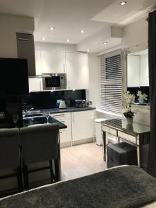 a kitchen with white cabinets and a table with a counter top at No 3 Victoria Apartment in Bowness-on-Windermere