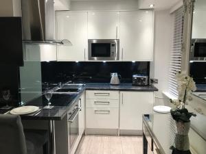 uma cozinha com armários brancos e um balcão preto em No 3 Victoria Apartment em Bowness-on-Windermere
