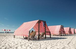 una fila de tiendas rojas y blancas en una playa en The Virginia and Cottages en Cape May