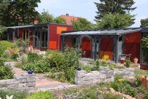 einen Garten vor einem roten Gewächshaus in der Unterkunft mein kleinHOTEL in Herbstein