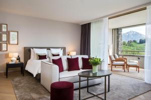 Bürgenstock Hotels & Resort - Waldhotel & Spa في بورغنستوك: غرفة نوم مع سرير وغرفة معيشة