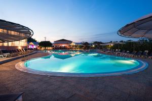 - une grande piscine avec des chaises et des parasols la nuit dans l'établissement Panorama Sidari, à Sidari