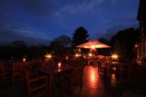 a patio with tables and umbrellas at night at Aberdunant Hall in Porthmadog