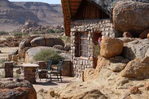 ein Steinhaus mit Tisch und Stühlen in der Wüste in der Unterkunft Gondwana Canyon Lodge in Kanebis + 48 Fotos