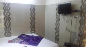 um quarto com uma cama com lençóis roxos e uma televisão em Hotel Ashoka em Ajmer