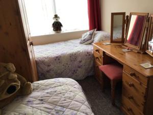 a bedroom with two beds and a desk with a mirror at 9 Gunfleet court in Clacton-on-Sea