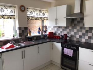 una cocina con armarios blancos y encimeras negras en 9 Gunfleet court, en Clacton-on-Sea