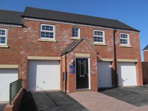 a red brick house with four garage doors at The Robin Coach House by RentMyHouse in Hereford