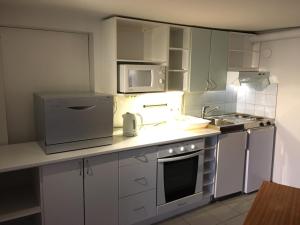 a kitchen with white cabinets and a stove and microwave at Yrjänäntie Home Apartment in Oulu