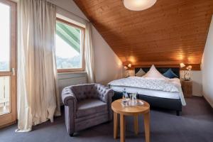 a bedroom with a bed and a chair and a table at Gartenhotel Salzach in Burghausen