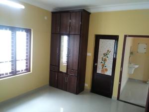 a bathroom with wooden cabinets and a toilet and a door at Sowparnika N.V Nagar Peroorkada in Trivandrum