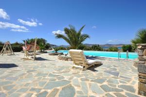 a patio with two chairs and a swimming pool at Parian Holiday Villas in Pounda