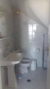 uma casa de banho branca com um lavatório e um WC em Vivlos. Maisonette with View em Vívlos