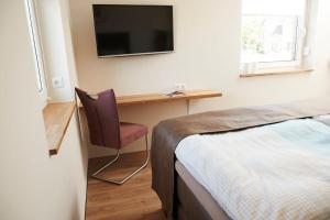een slaapkamer met een bed en een bureau met een televisie bij FraulindnerFerien Doppelzimmer Lüneburg in Westergellersen