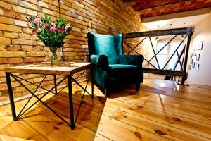 a room with a chair and a table with a vase of flowers at Apartamenty I SORAU in Żary