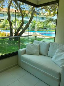 een witte bank in een kamer met een groot raam bij Carneiros Resort Beira Mar Térreo in Praia dos Carneiros