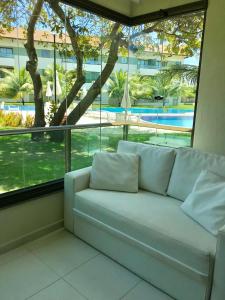 a white couch in a room with a large window at Carneiros Resort Beira Mar Térreo in Praia dos Carneiros