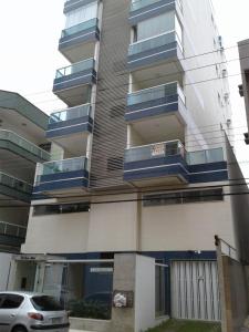 un edificio con balcones azules y un coche aparcado delante en Edifício Corte Real, en Guarapari