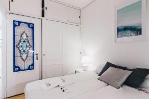 a white bedroom with a bed and a door at Garai Apartment by People Rentals in Bilbao