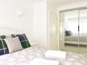 een witte slaapkamer met een bed en een spiegel bij Splendid Fitzrovia W1 Heart of Central London 1-Bed. Free Wifi in Londen