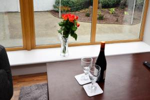 Apartment 709 Letterfrack في ليترفراك: زجاجة من النبيذ و مزهرية مع الزهور على الطاولة