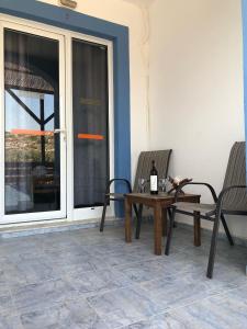 um pátio com 2 cadeiras e uma mesa com uma garrafa de vinho em Kedros Rooms em Prasonisi