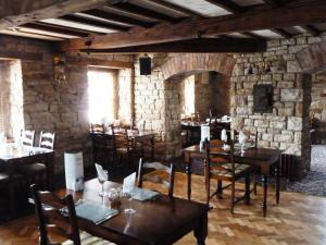 a restaurant with wooden tables and chairs and a stone wall at Batemans Mill Hotel & Restaurant in Clay Cross