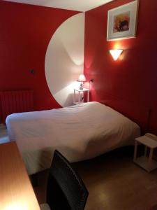 a bedroom with a bed with a red wall at Hôtel du Lion d'Or in Marmande