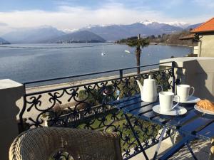 Villa Maria Lago Maggiore في Reno Di Leggiuno: طاولة مع أكواب القهوة على شرفة مطلة على المياه