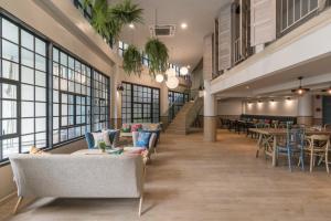 eine Lobby mit Sofas, Tischen und Fenstern in der Unterkunft The Blanket Hotel Phuket Old Town in Phuket