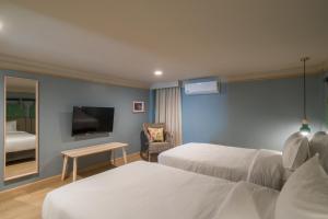 ein Hotelzimmer mit zwei Betten und einem Fernseher in der Unterkunft The Blanket Hotel Phuket Old Town in Phuket