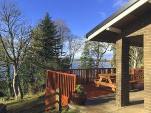 eine Holzterrasse mit einem Picknicktisch und einem Zaun in der Unterkunft Manor House Marine & Cottages in Irvinestown